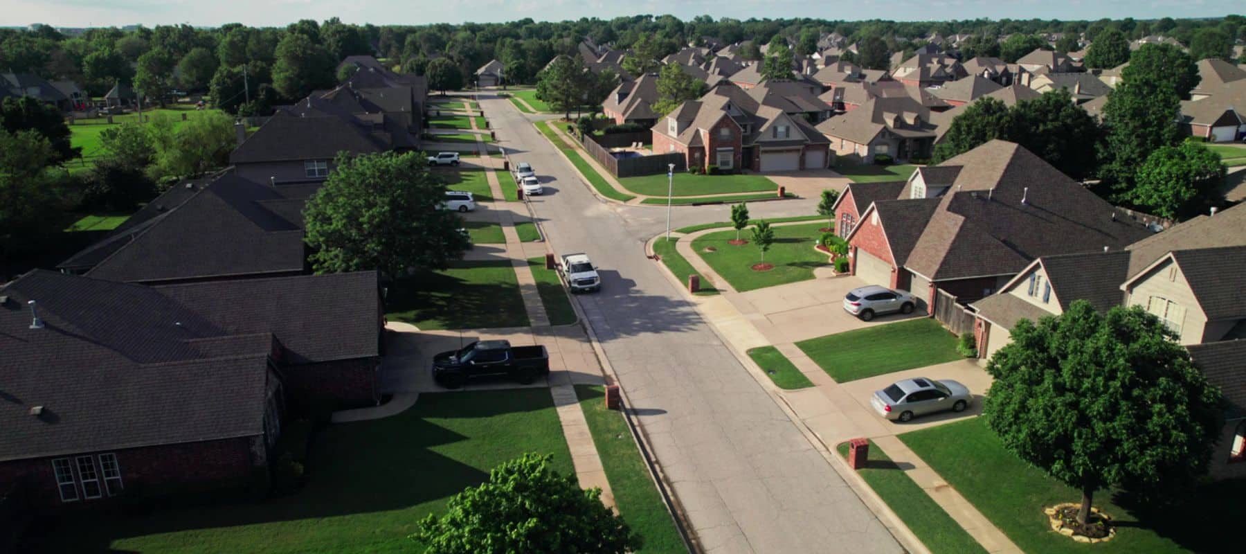 Aerial view of a quiet suburban neighborhood with neatly manicured lawns, driveways, and family homes